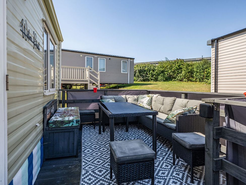 An outdoor seating area with a table and cushioned seats at 3 Bed Sleeps 8 Sea View Pets Parking Reighton Gap near Filey