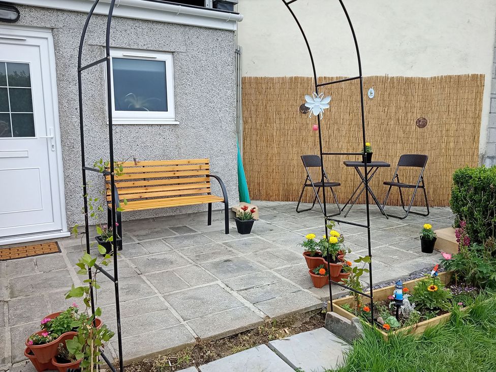 A garden with a bench, table, chairs, and potted plants at Studio Sleeps 2 with Parking and Garden Trewidland near Liskeard