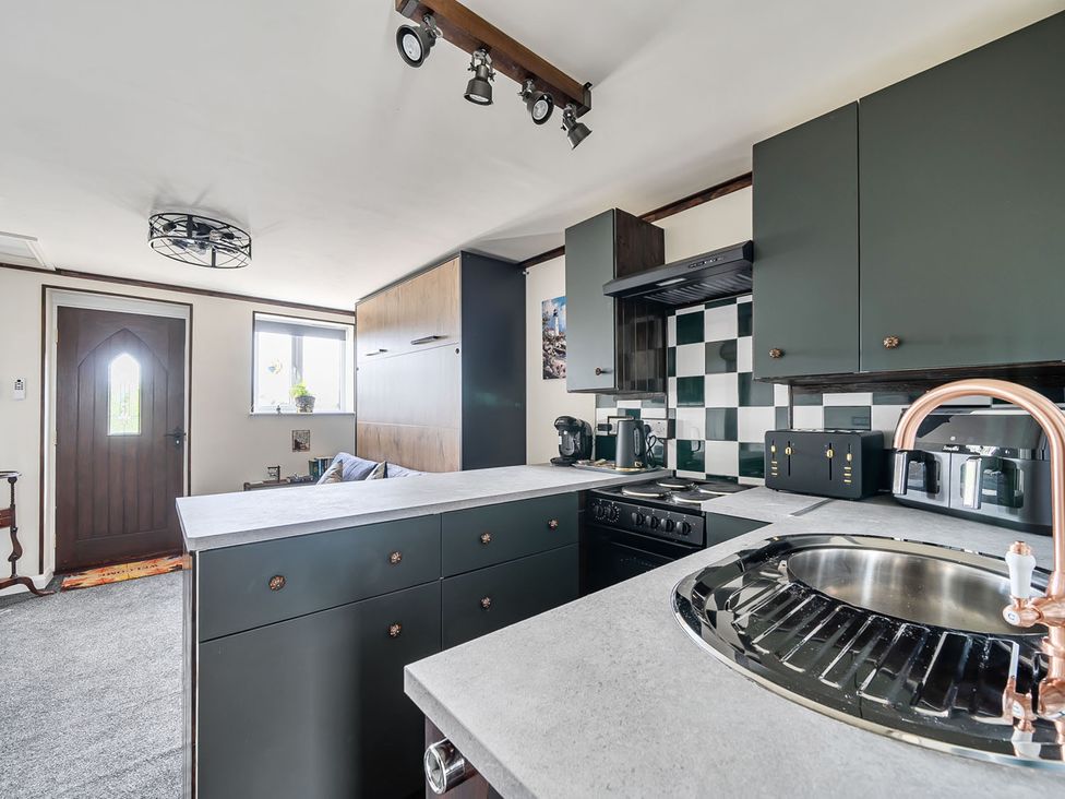 A kitchen with a stove, sink, and kitchen cabinets at Studio Sleeps 2 with Parking and Garden Trewidland near Liskeard