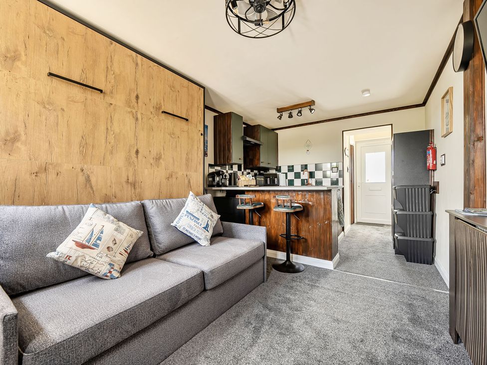 A living room with a sofa and kitchen counter at Studio Sleeps 2 with Parking and Garden Trewidland near Liskeard