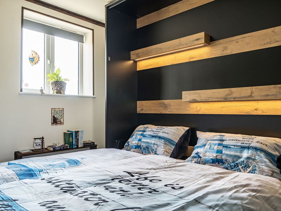 A bedroom with a bed, bedside table, books, and a plant at Studio Sleeps 2 with Parking and Garden Trewidland near Liskeard