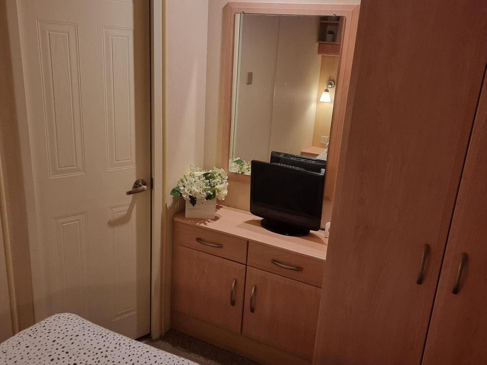 A bedroom with a dresser and television at Chalet Sleeps 6 swimming pool Thorness Bay