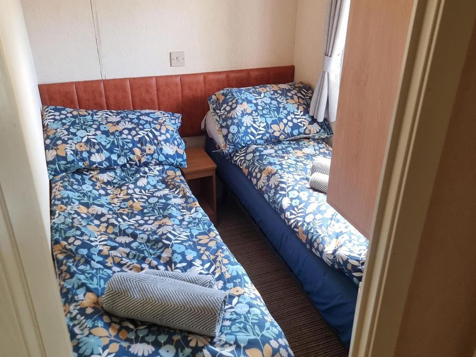 A bedroom with two single beds and a bedside table at Chalet Sleeps 6 swimming pool Thorness Bay