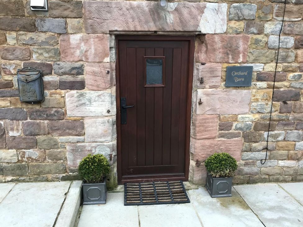 An entryway with a brown door and stone wall at Orchard Barn in Waterhouses