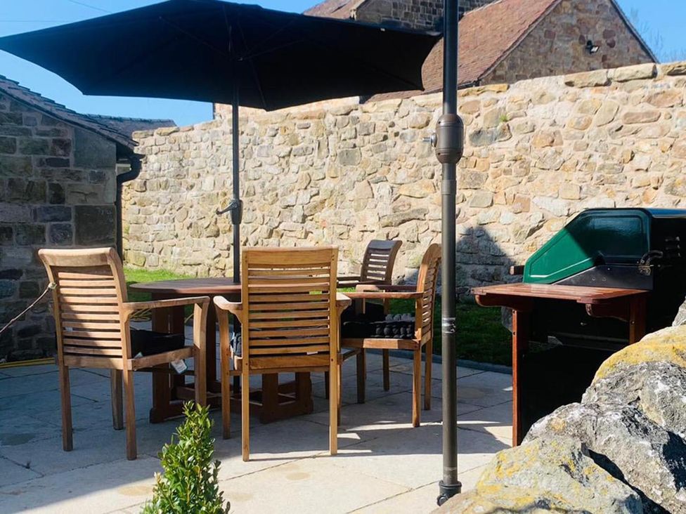 An outdoor dining area with a table, chairs, and a barbecue grill at Barn Sleeps 4 Parking Near Alton Towers in Waterhouses