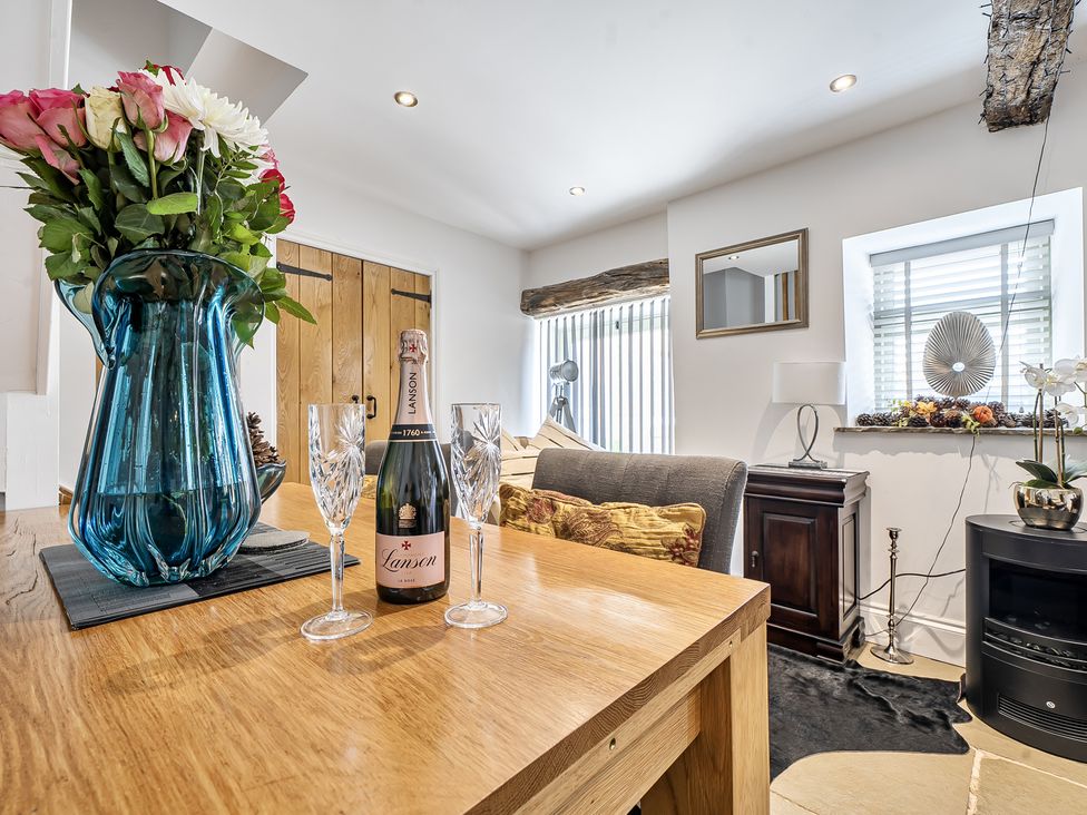 A living room with a vase of flowers and champagne at Barn Sleeps 4 Parking Near Alton Towers in Waterhouses