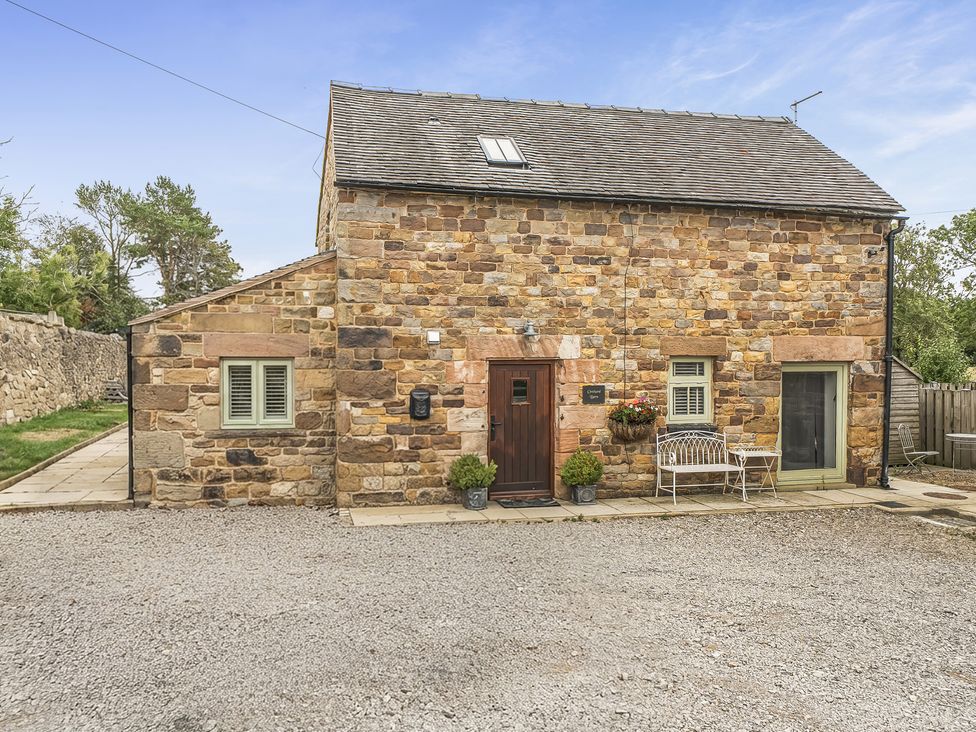 An outdoor view of a stone cottage with a door and bench at Barn Sleeps 4 Parking Near Alton Towers Waterhouses