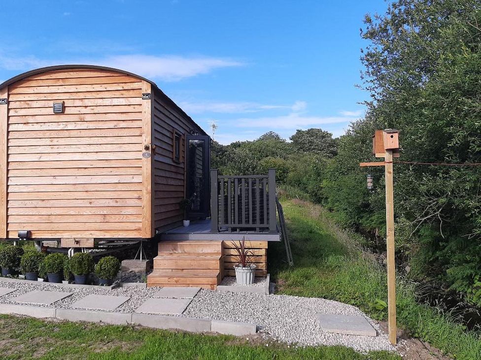 A cabin with a deck and garden features at Min yr Afon Cabin Sleeps2 Hot Tub Parking in Gwalchmai