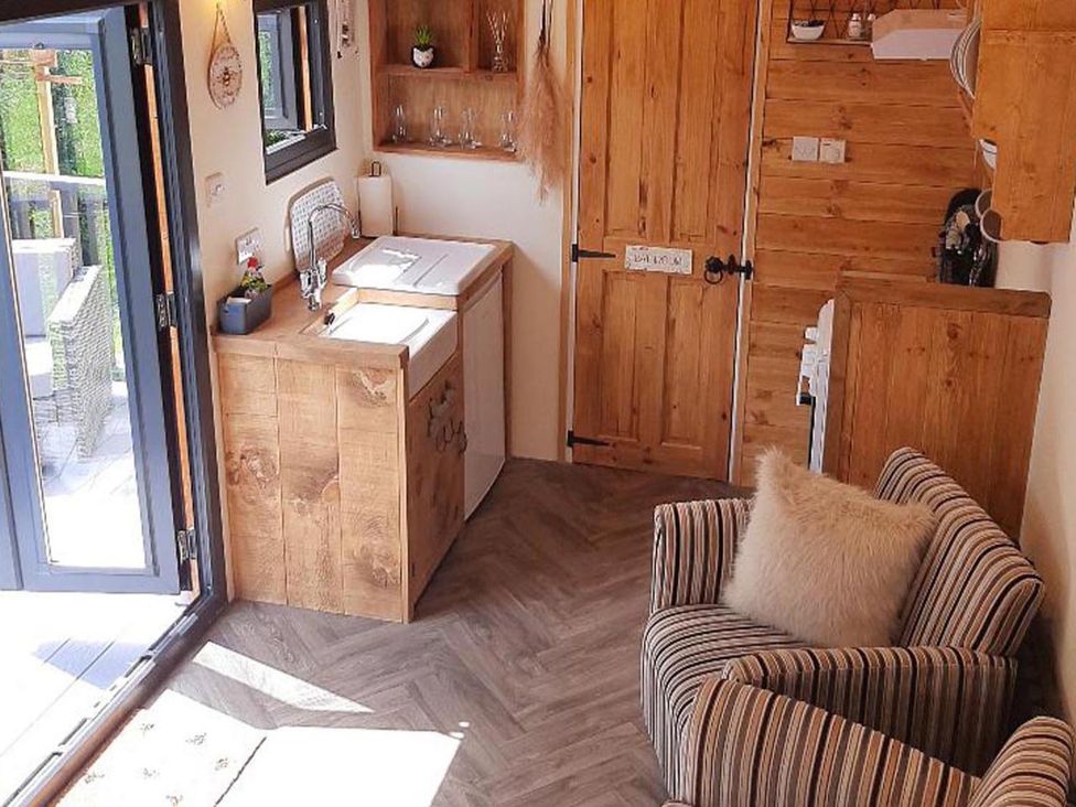 A kitchen with wooden cabinets and a sink at Min yr Afon Cabin Sleeps2 Hot Tub Parking in Gwalchmai