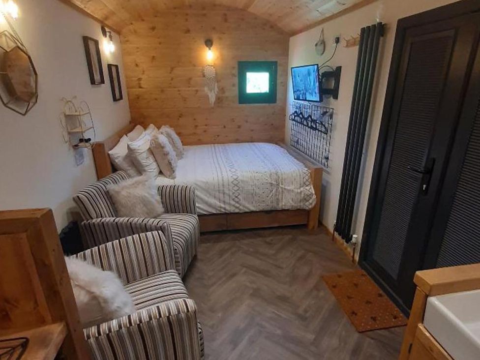 A bedroom with a bed and chairs at Min yr Afon Cabin Sleeps2 Hot Tub Parking in Gwalchmai