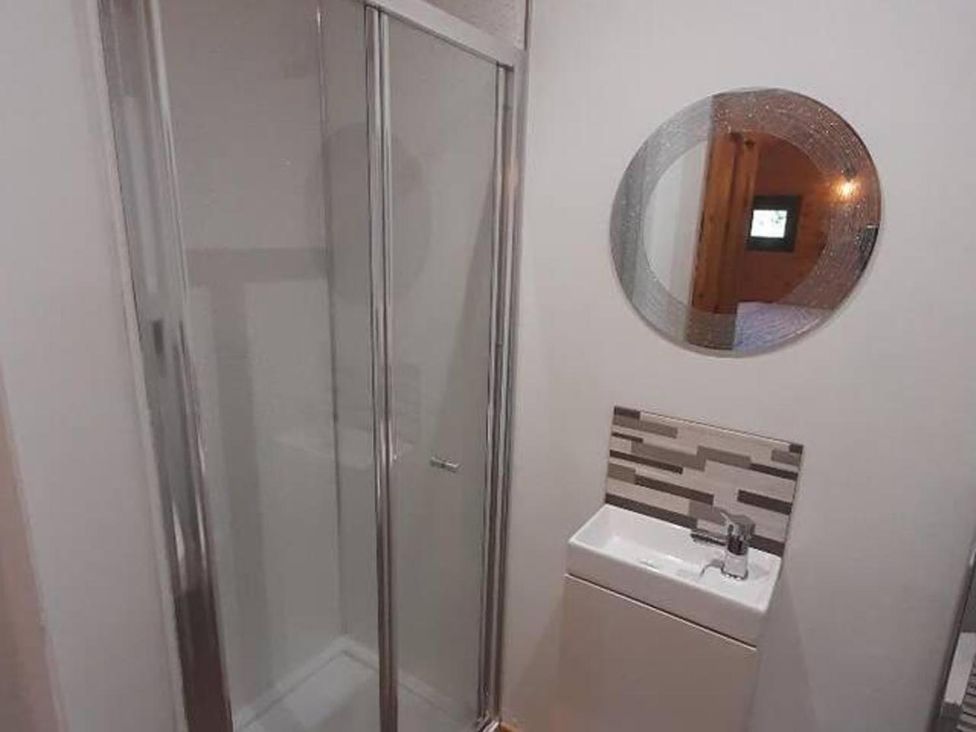 A bathroom with a shower, sink, and mirror at Min yr Afon Cabin Sleeps2 Hot Tub Parking Gwalchmai