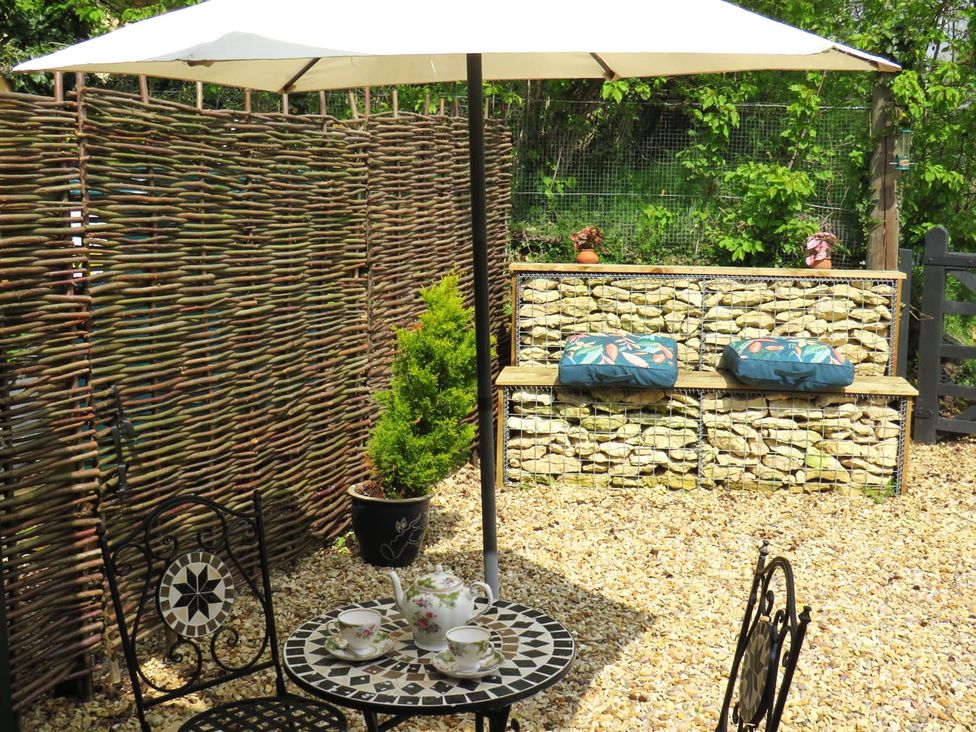 A table with chairs and an umbrella in a garden setting