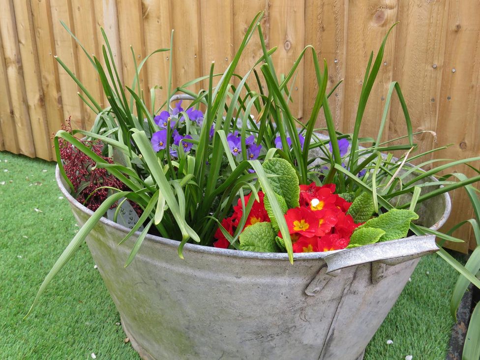 A planter with flowers and grass in a garden