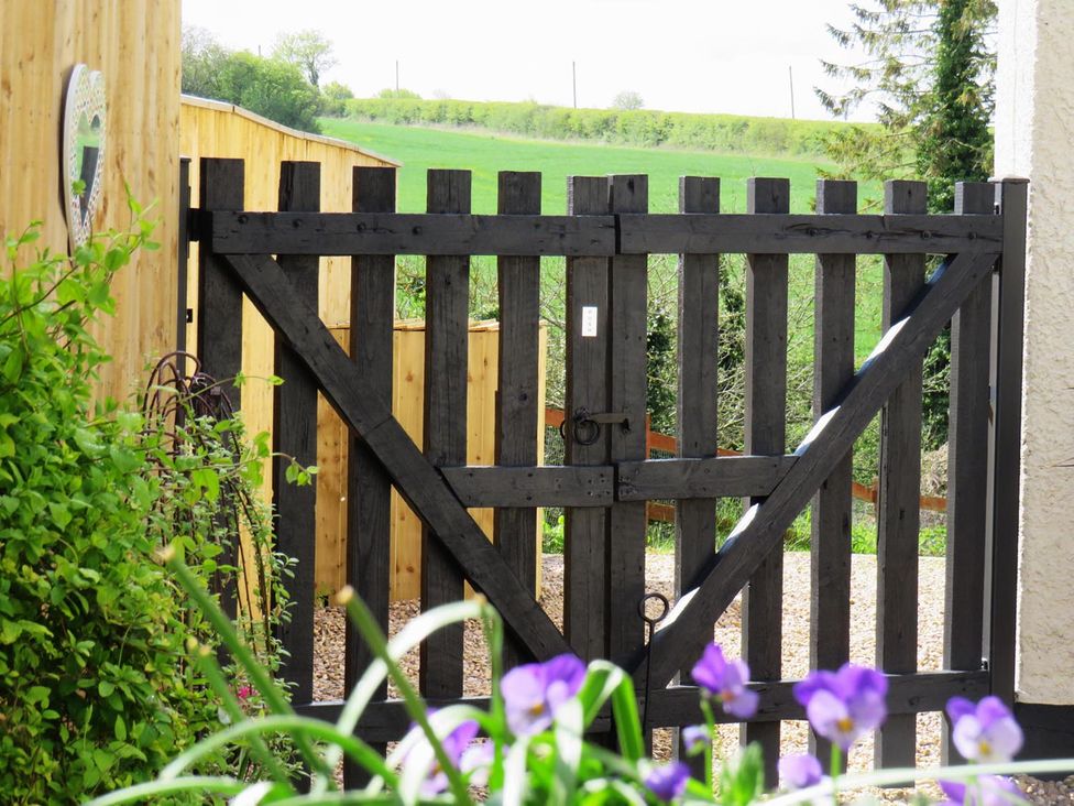 A wooden gate in a garden with flowers in the foreground