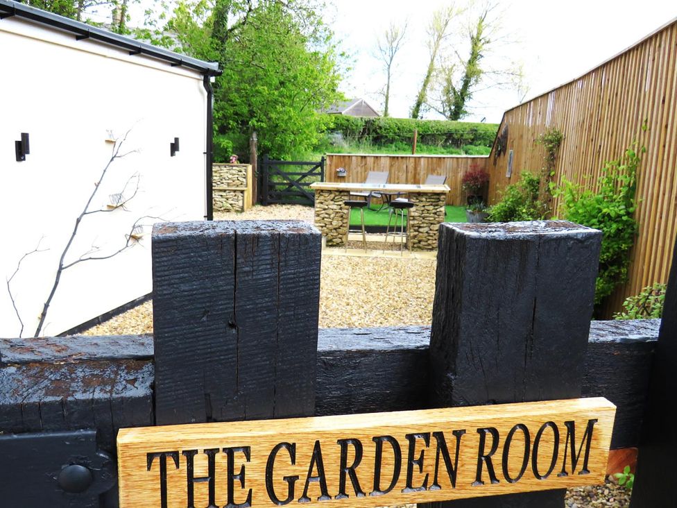 A garden with a stone wall and seating area at The Garden Room in 