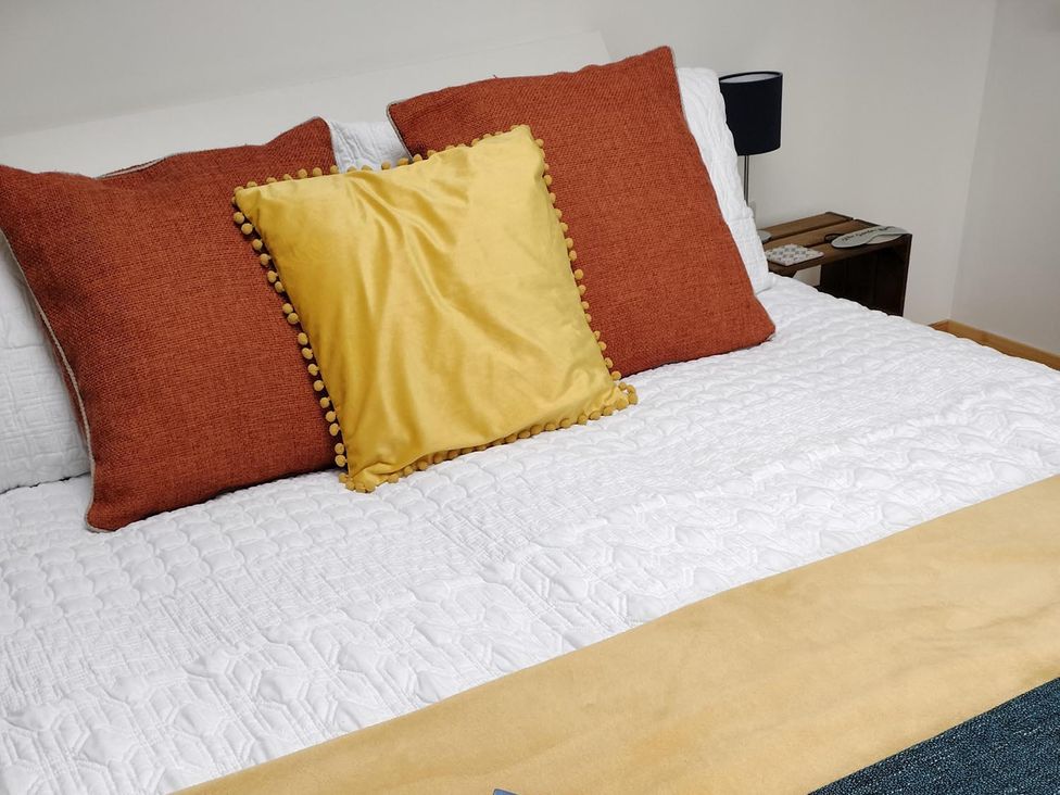 A bed with pillows and a side table in a bedroom