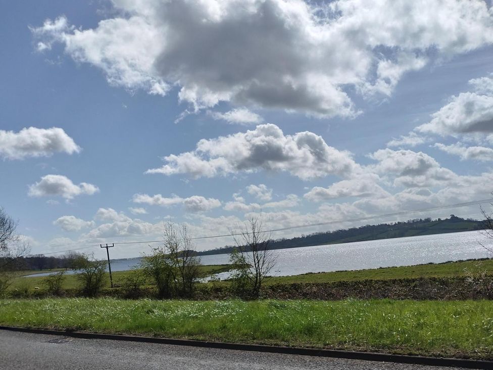 A scenic view of water and clouds by a roadside