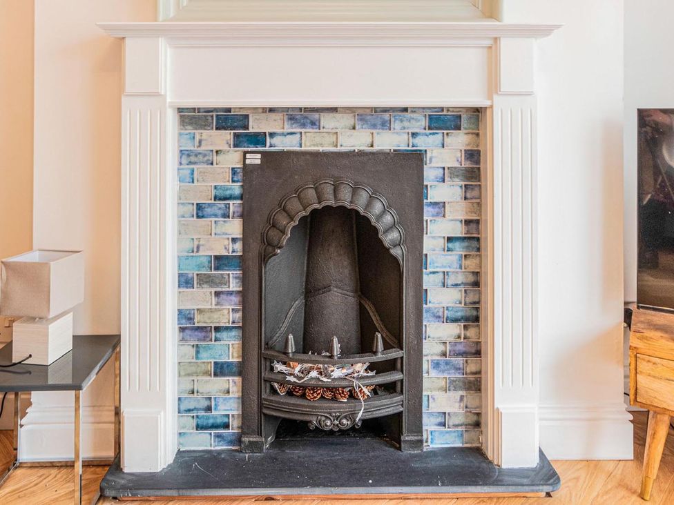 A fireplace with tiles and a side table at The Slipway Fowey Harbour with Garden Fowey