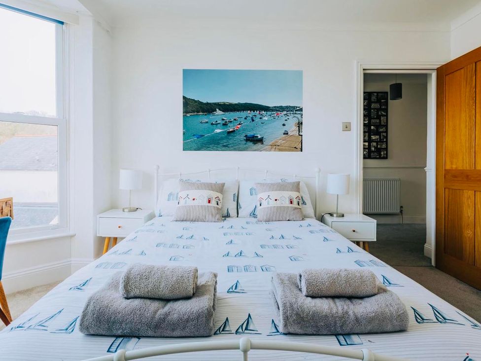 A bedroom with a bed and picture of a harbor at The Slipway Fowey Harbour with Garden Fowey