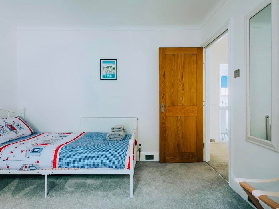 A bedroom with a bed and wooden door at The Slipway Fowey Harbour with Garden in Fowey