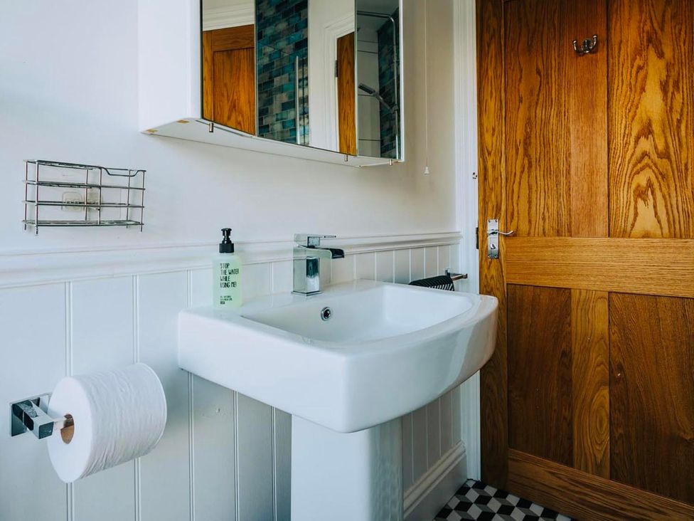 A bathroom with a wall-mounted sink and toilet roll at The Slipway Fowey Harbour with Garden Fowey