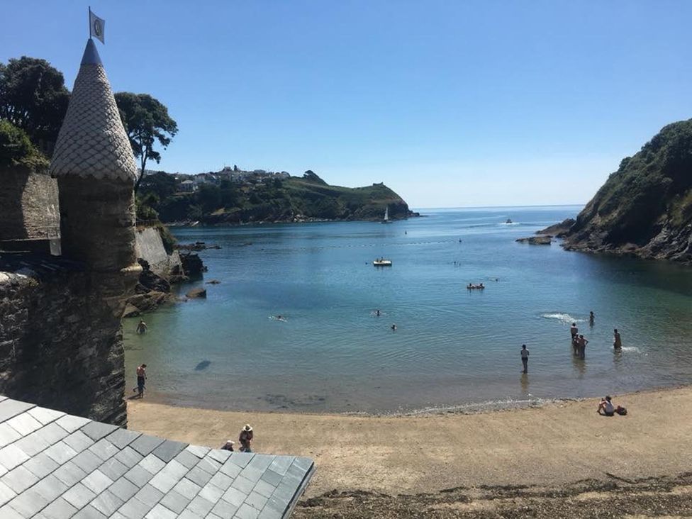 A beach scene with people swimming and boats at The Slipway Fowey Harbour with Garden Fowey