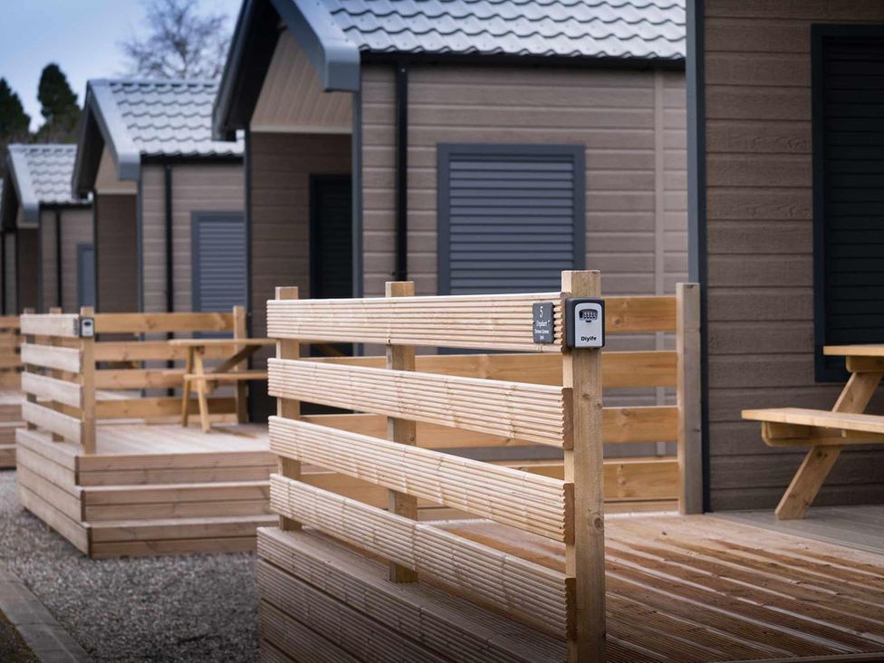 A wooden fenced area with cabins and seating at Selfcatering Lodge Inverness Sleeps 4 Inverness