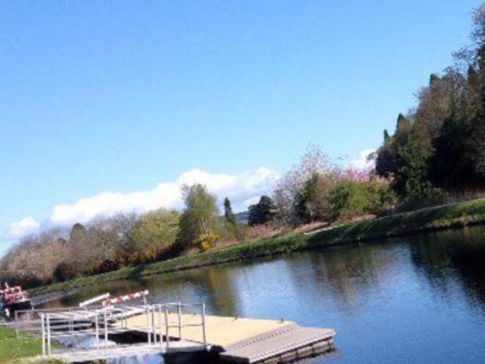 A river with a dock and trees at Selfcatering Lodge Inverness Sleeps 4 Inverness