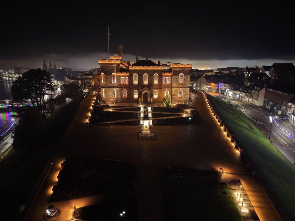A historic building illuminated at night with a Christmas tree and pathways at Selfcatering Lodge Inverness Sleeps 4 Inverness