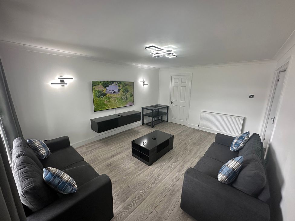 A living room with a television and coffee table at Family Garden Parking WiFi Sleeps 5 in Alloa