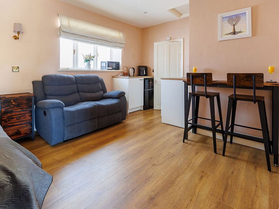 A living room with a sofa and bar stools at North Norfolk Garden Retreat with Private Hot Tub Crossdale Street near Cromer