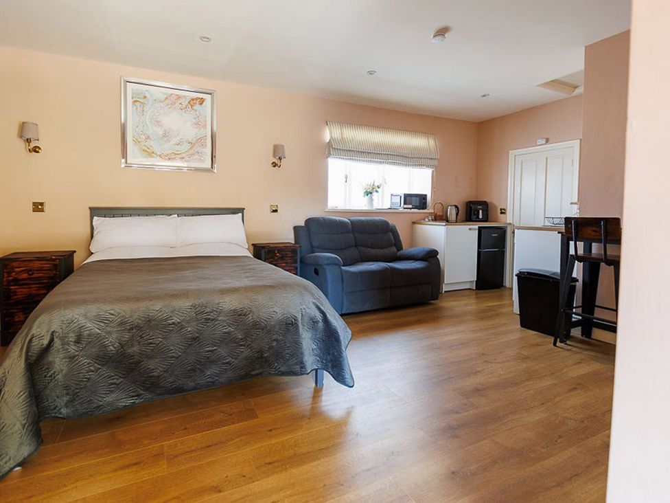 A bedroom with a bed and kitchenette at North Norfolk Garden Retreat with Private Hot Tub Crossdale Street near Cromer