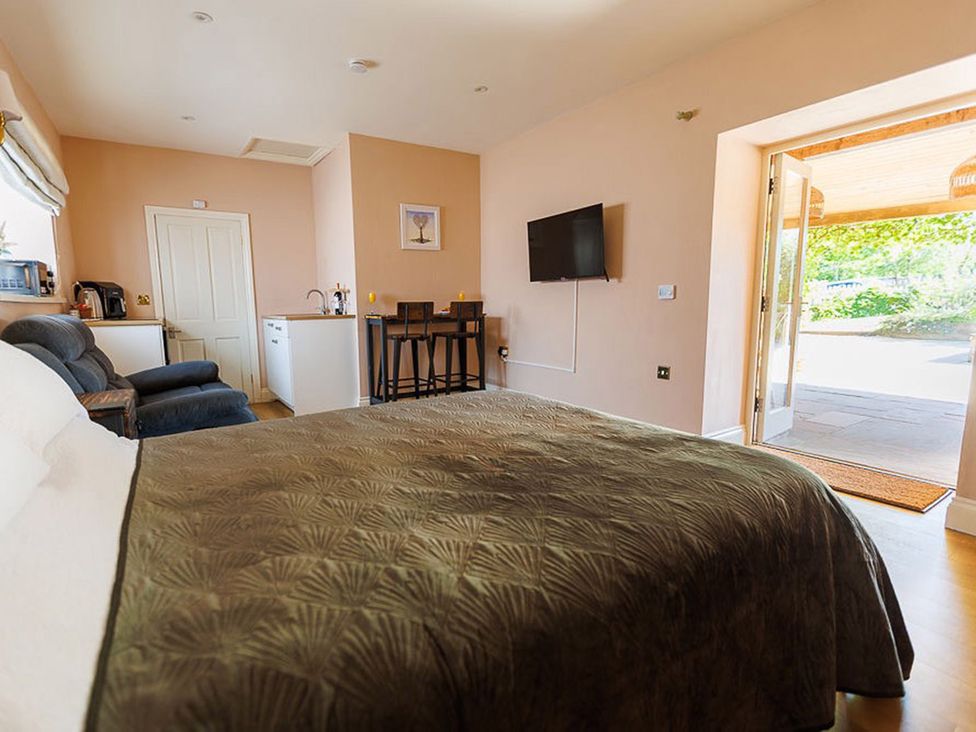 A bedroom with a bed and kitchenette at North Norfolk Garden Retreat with Private Hot Tub Crossdale Street near Cromer