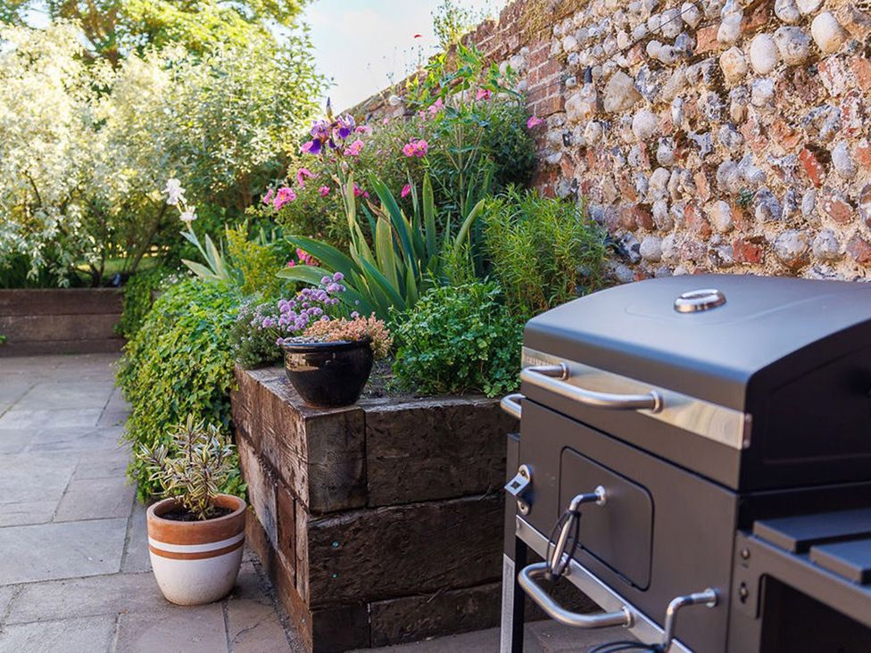 A garden with a barbecue grill and flower beds at North Norfolk Garden Retreat with Private Hot Tub Crossdale Street near Cromer