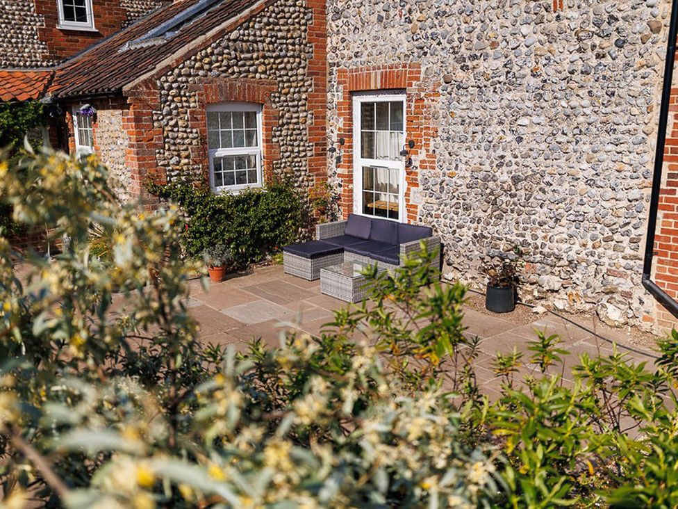 An outdoor seating area next to a stone wall at North Norfolk Garden Retreat with Private Hot Tub Crossdale Street near Cromer