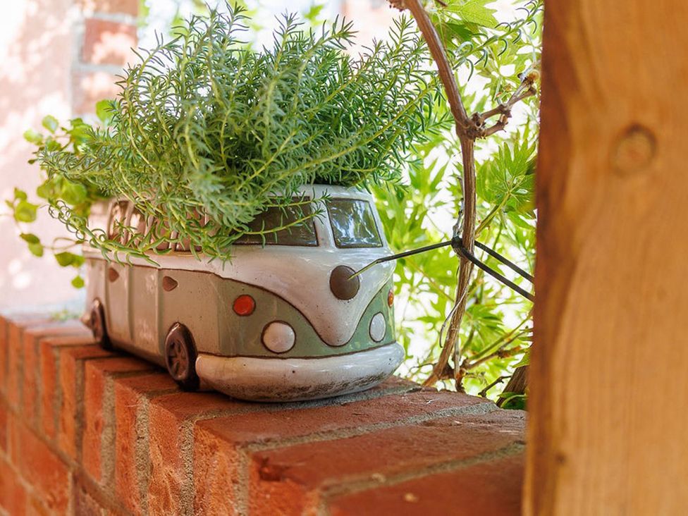A decorative flower pot shaped like a van on a brick wall in North Norfolk Garden Retreat with Private Hot Tub Crossdale Street near Cromer