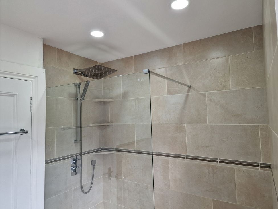 A shower area with tile walls and a glass shower door at the property in 