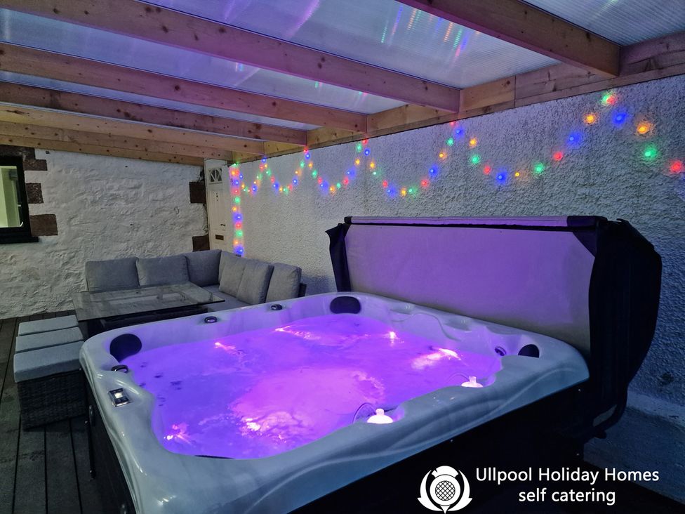 A hot tub and seating area with lights at Ullpool Holiday Homes self catering