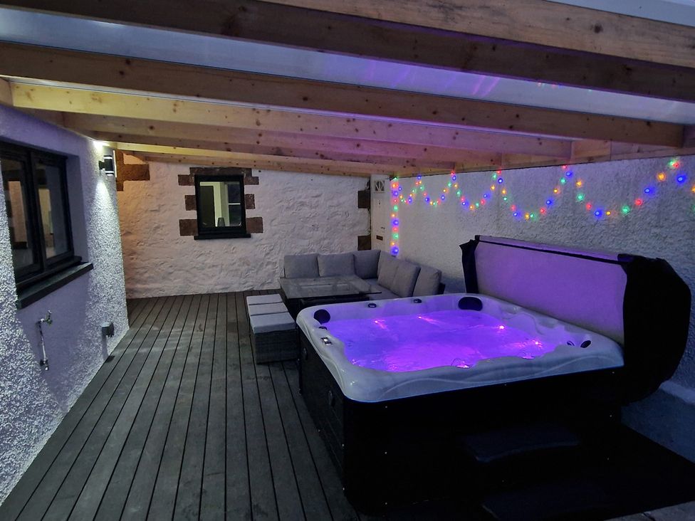An outdoor patio with a hot tub and seating area at the property