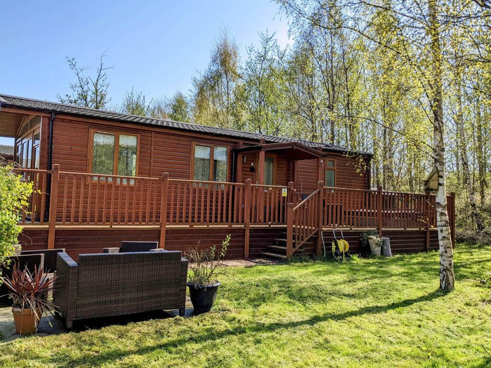 A lodge with a deck and garden furniture at Felmoor Park Northumberland Lodge with Hot Tub near Felton