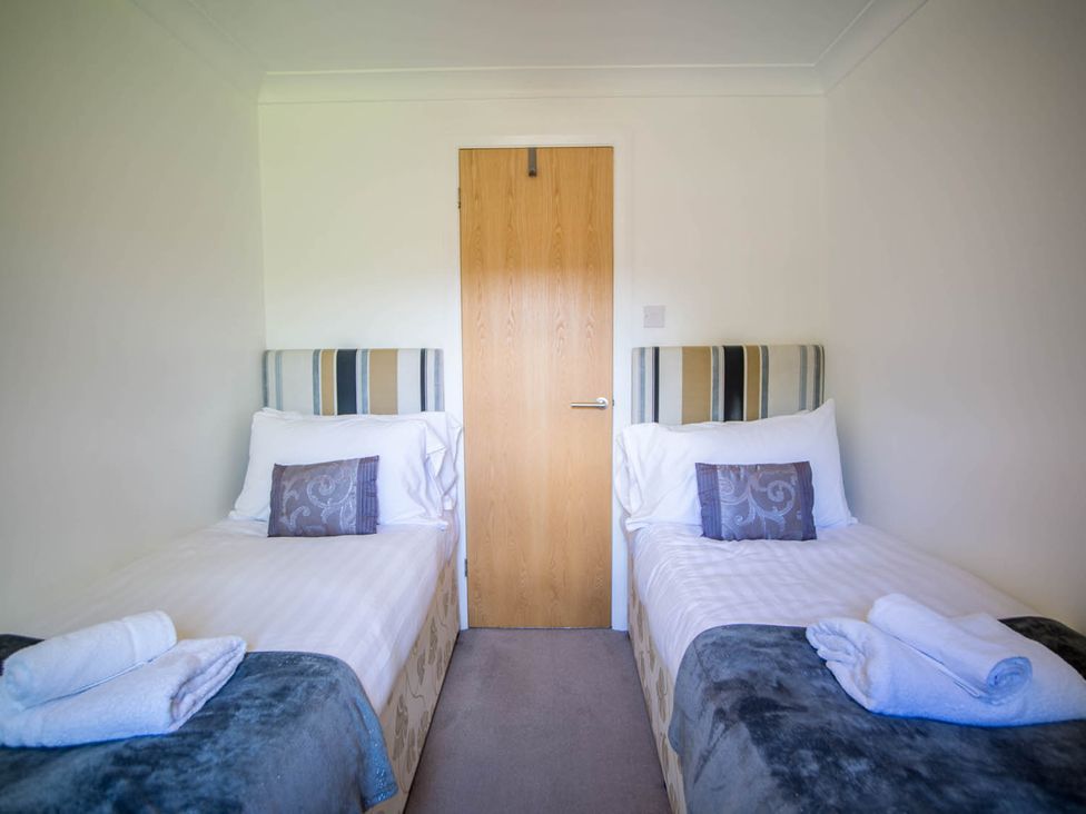 A bedroom with twin beds and a door at Felmoor Park Northumberland Lodge with Hot Tub Felmoor Park near Felton