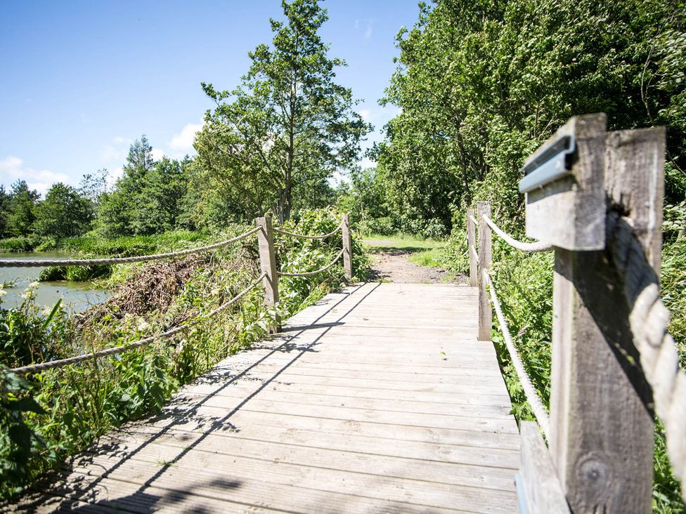 A wooden bridge with rope railing near water at Felmoor Park near Felton
