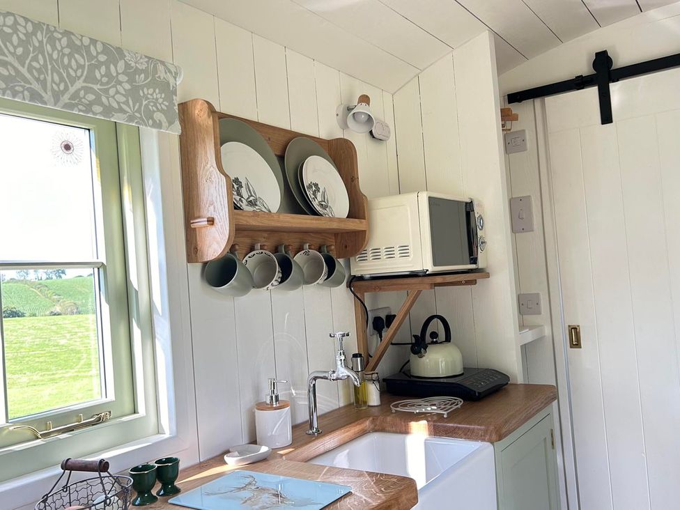 A kitchen with a window, shelves, plates, and a sink at the property