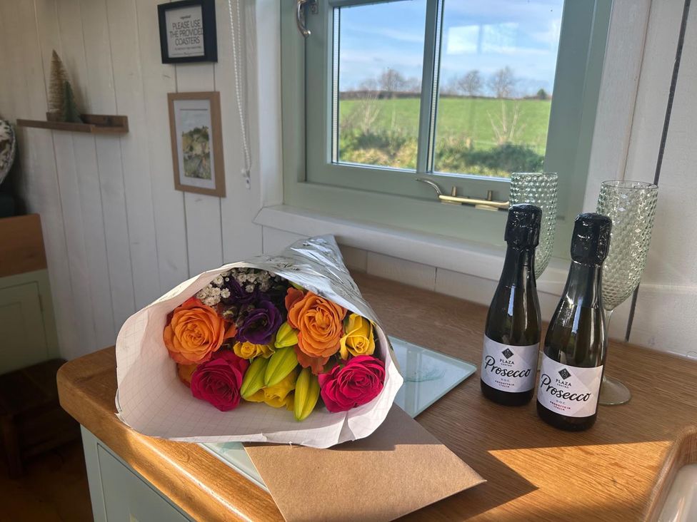 A bouquet of flowers and prosecco bottles on a table in a kitchen