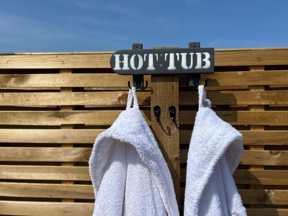 A sign and towels hanging on hooks at an outdoor hot tub area