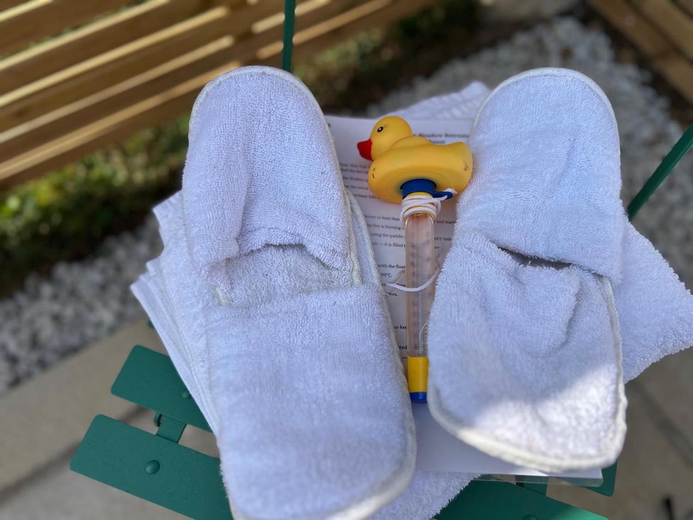 A pair of slippers and a rubber duck toy with instructions on a green table