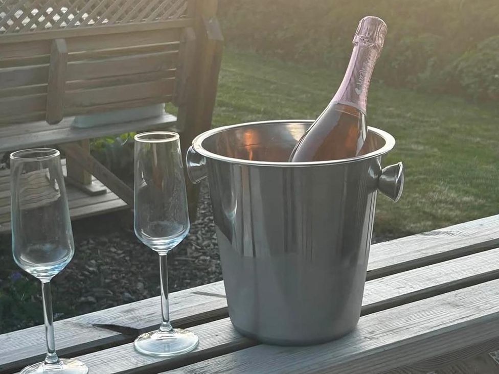 An ice bucket with a champagne bottle and flutes on a table