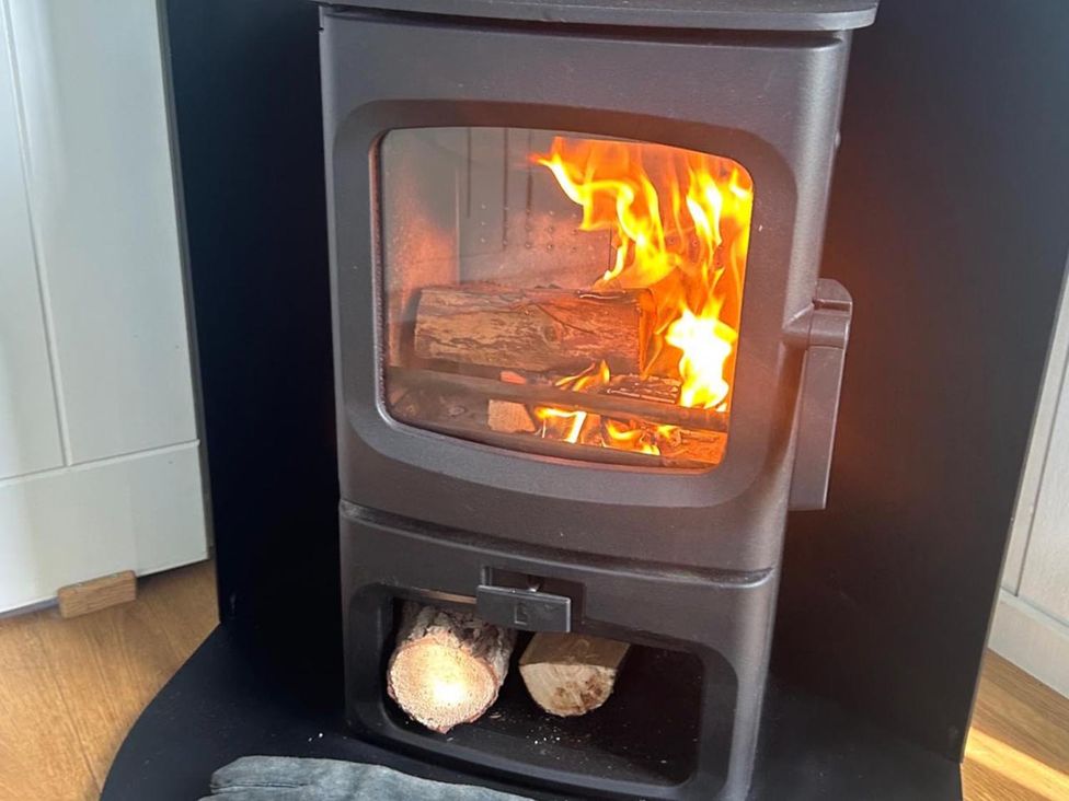 A wood stove with flames and firewood at a residence