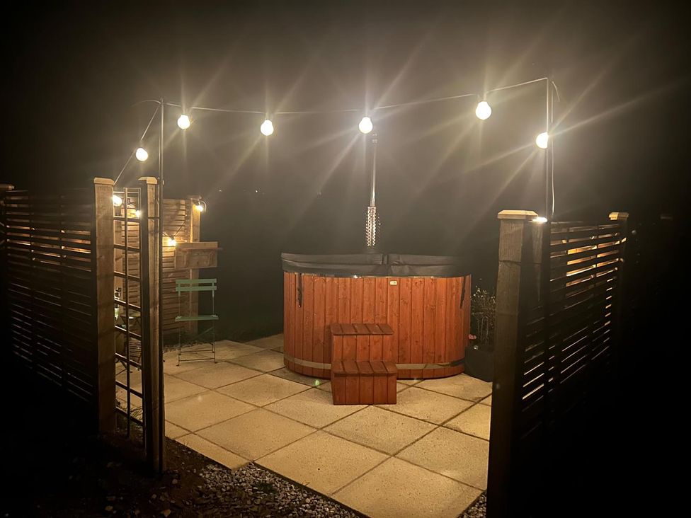 An outdoor area with a hot tub, patio and string lights