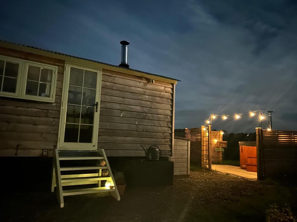 A wooden cabin with outdoor lighting at the entrance at a property in an undisclosed location